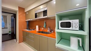 Una cocina moderna con microondas, hervidor y lavabo.