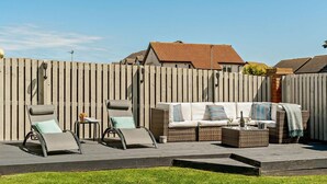 A patio with two lounge chairs, a sofa, and a small table. - 4 Bed in Seahouses (oc-o27867) (Seahouses)