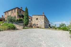 Un bâtiment historique en pierre, avec une allée gravillonnée, un escalier et un panneau indiquant qu’il est interdit de se garer.