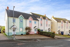 A row of colorful terraced houses with a paved driveway and a street lamp.