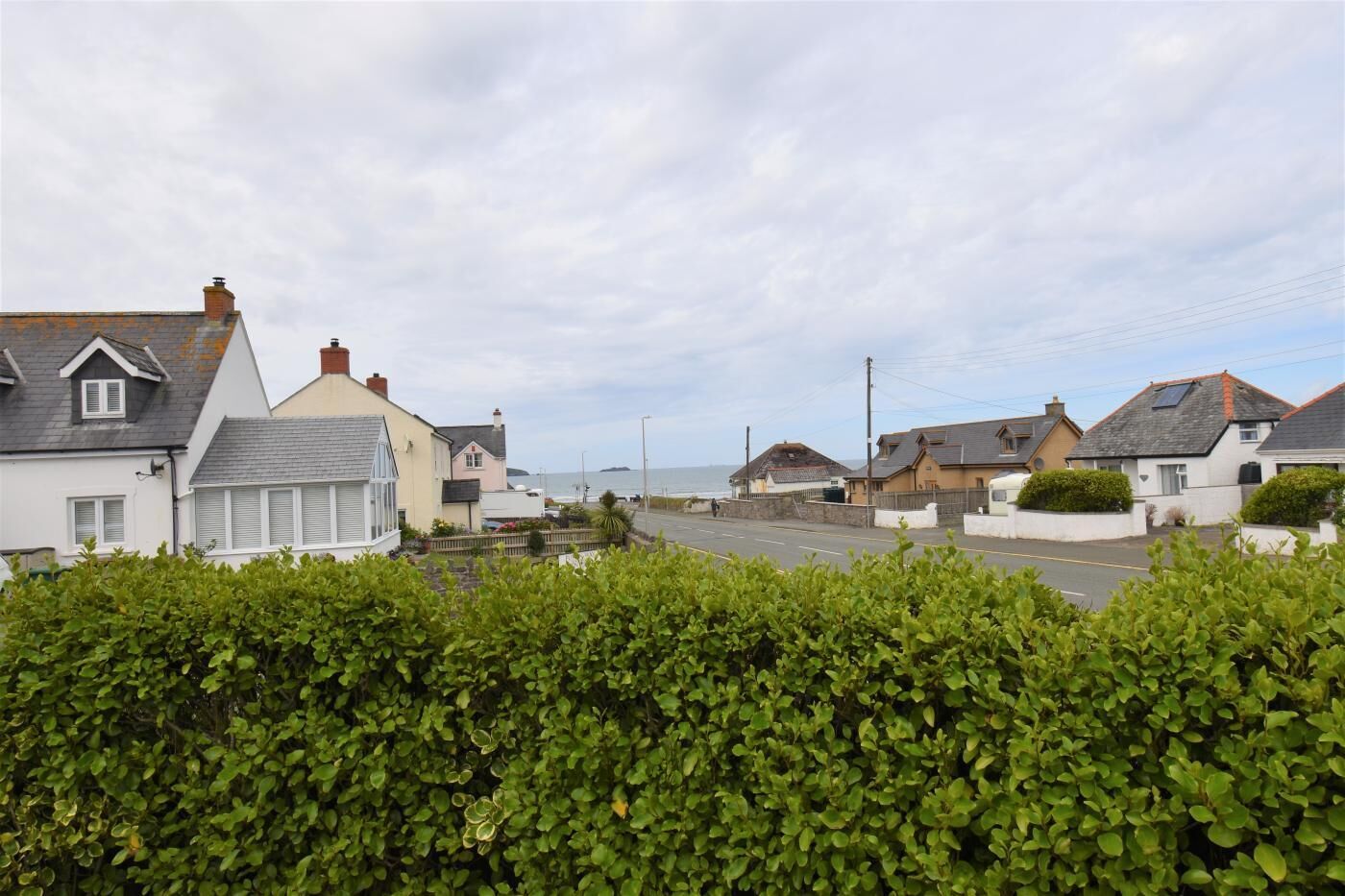 Un quartier résidentiel situé sur la côte, avec des maisons, une route et une vue sur la mer.