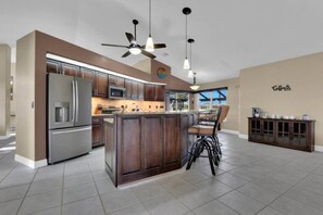 A modern kitchen with a central island, stainless steel appliances, and a bar area. - Tuscan Treasure Bike, Kayaks, Peddleboat Included (Cape Coral)