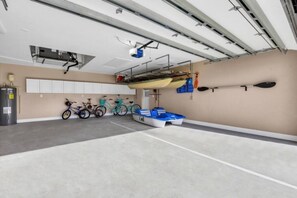 A spacious indoor area with a concrete floor, bicycles, kayaks, and a water heater. - Tuscan Treasure Bike, Kayaks, Peddleboat Included (Cape Coral)