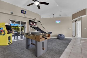 A room with a foosball table, a TV, and a ceiling fan. - Tuscan Treasure Bike, Kayaks, Peddleboat Included (Cape Coral)