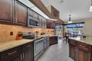 A modern kitchen with dark wood cabinets, stainless steel appliances, and a large island. - Tuscan Treasure Bike, Kayaks, Peddleboat Included (Cape Coral)