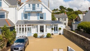 A two-story house with a balcony, a driveway, and a car parked in front. - 9 Bed in Instow (oc-a27886) (Instow)