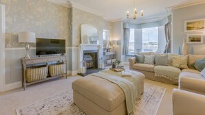 A living room with a fireplace, a television, and a sofa. - 9 Bed in Instow (oc-a27886) (Instow)
