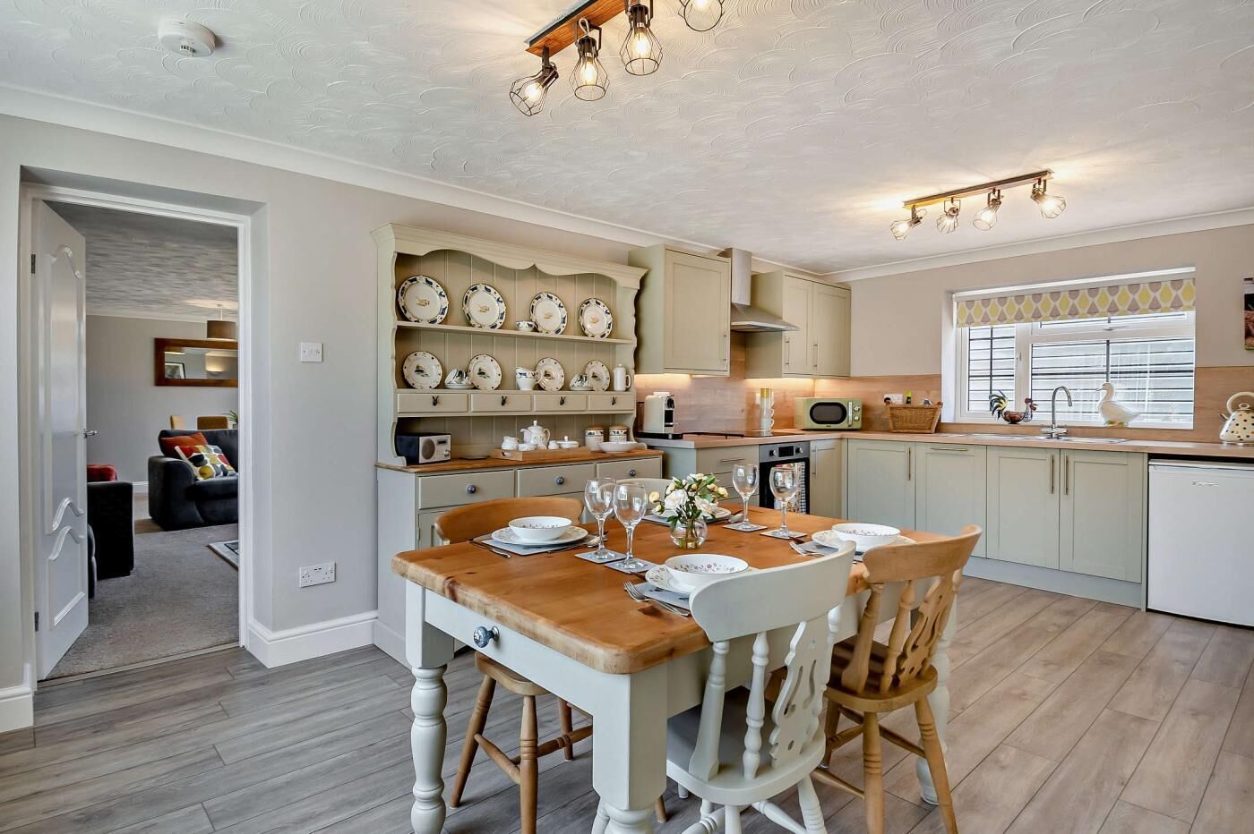 A modern kitchen with a dining table set for four, a built-in oven, and a microwave.