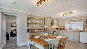 A modern kitchen with a dining table set for four, a built-in oven, and a microwave. - 2 Bed in Gimingham (oc-h27869) (Gimingham)