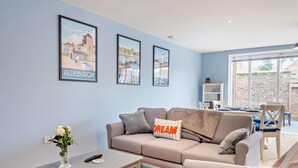 A modern living room with a grey sofa, a coffee table, and framed cityscape pictures on the wall. - 2 Bed in Southwold (oc-t27861) (Southwold)