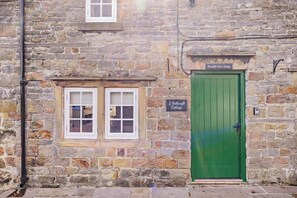 A stone building with a green door, two windows, and a sign indicating "2 Middleton Cottages". - 1 Bed in Warslow (oc-h27591) (Warslow and Elkstones)