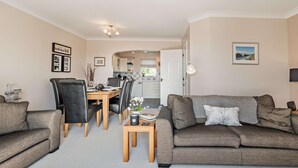 A living room with a sofa, a dining table with chairs, and a kitchen in the background. - 3 Bed in Broad Haven (oc-p27926) (Broad Haven)