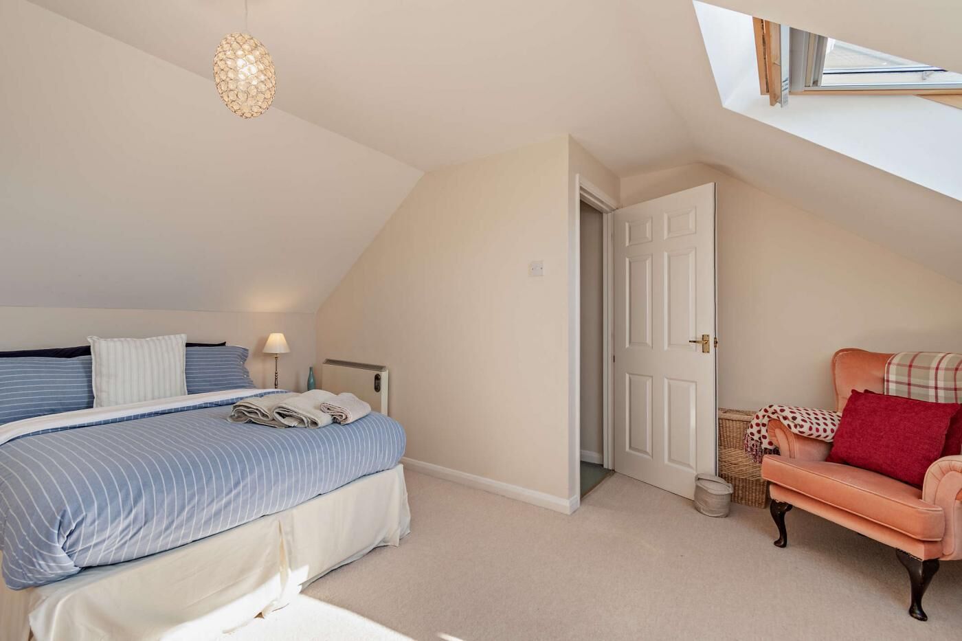 Een slaapkamer met een bed, een stoel, een lamp en een deur.
