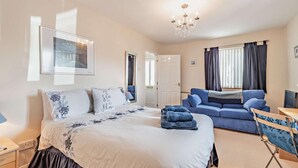 A bedroom with a large bed, a blue sofa, a desk, and a chandelier. - 3 Bed in Broad Haven (oc-p27926) (Broad Haven)