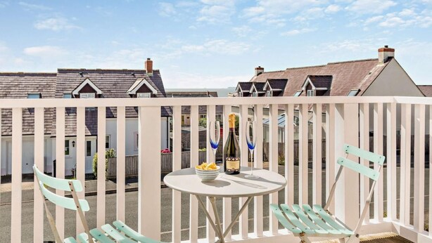 A balcony with a table, two chairs, and a bottle of champagne. - 3 Bed in Broad Haven (oc-p27926) (Broad Haven)