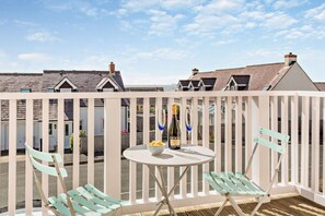 Un balcon avec une table, deux chaises et une bouteille de champagne.