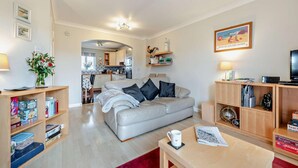 Una sala de estar moderna con un sofá, una mesa de centro y estanterías con libros y objetos decorativos.