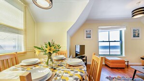 A dining area with a table set for four, a TV, and a view of the sea through large windows. - 2 Bed in Broad Haven (oc-s27911) (Broad Haven)