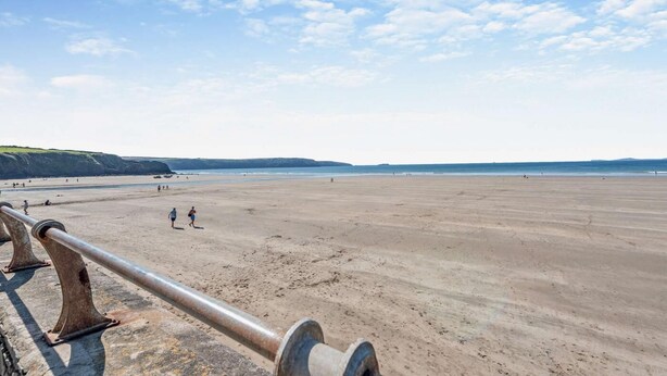 A wide, sandy beach with a metal railing in the foreground. - 2 Bed in Broad Haven (oc-s27911) (Broad Haven)