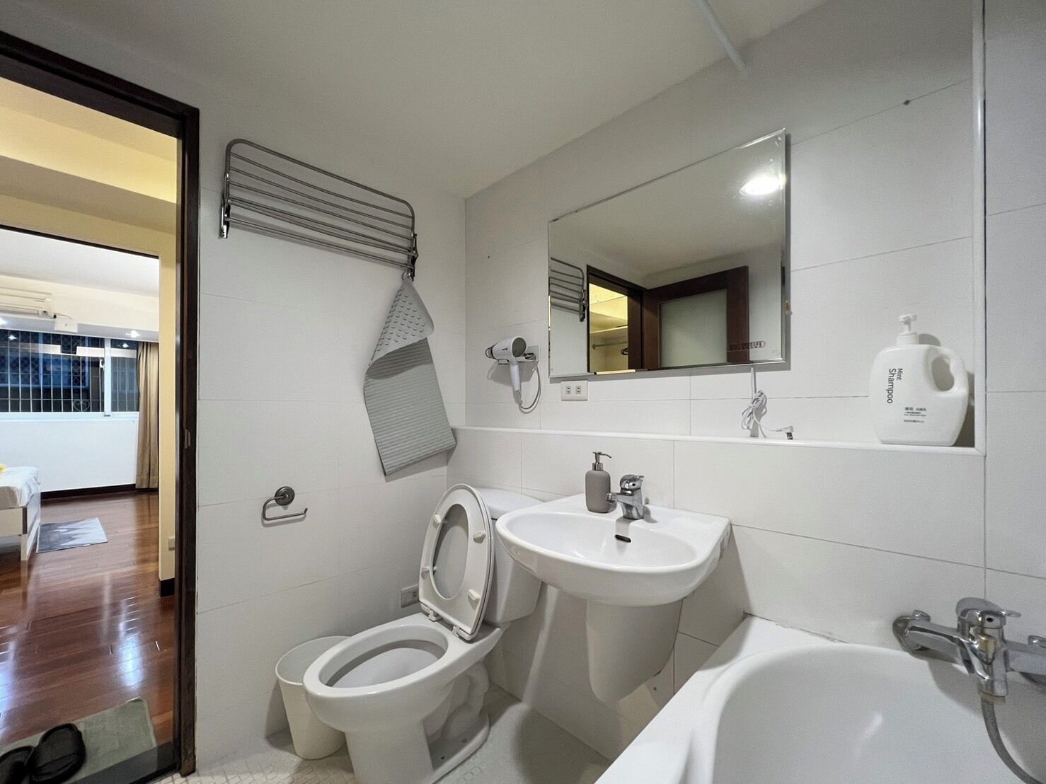 A modern bathroom with a toilet, sink, and bathtub. There is a towel rack and a mirror above the sink.