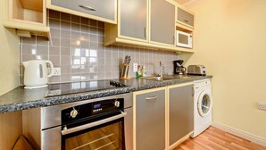 A compact kitchen with a built-in oven, microwave, and a washing machine.