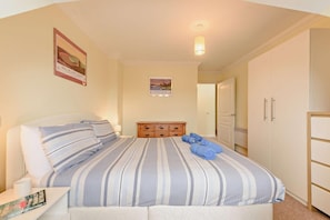 A hotel room with a bed, a nightstand, a dresser, and a wardrobe.