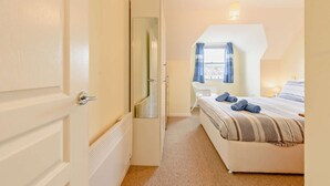 A bedroom with a bed, a window with curtains, a bedside lamp, and a mirror. - 2 Bed in Broad Haven (oc-s27956) (Broad Haven)