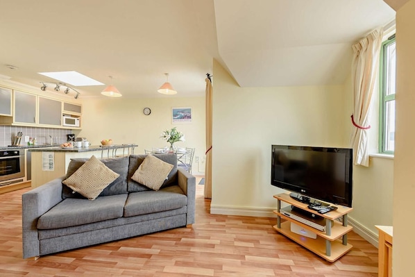 A modern living room with a grey sofa, a flat-screen TV, and a wooden TV stand.