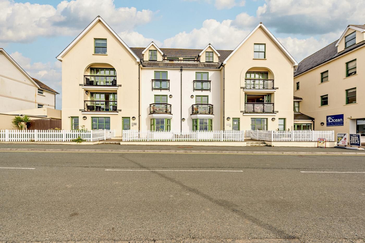 A multi-story hotel with balconies, a white picket fence, and a sign for a seafood restaurant.