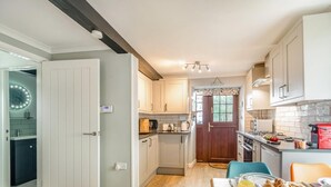 Een moderne keuken met witte kastjes, een houten deur en een ontbijtgedeekte eettafel.
