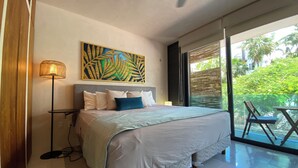 Ein Schlafzimmer mit einem großen Bett, einer Stehlampe, einem Deckenventilator und Blick auf Grün.