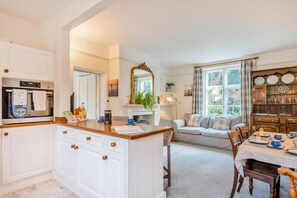 A cozy kitchen with a central island, a dining area with a table set for two, and a comfortable seating area with a sofa. - 2 Bed in Holt (oc-m27990) (Holt)