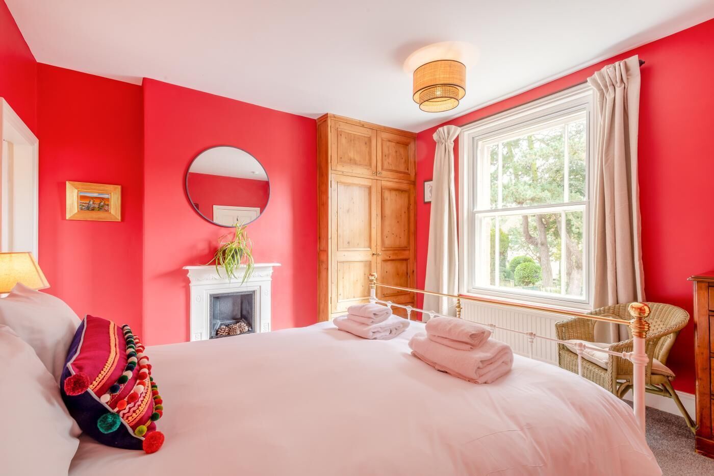 Une chambre avec un grand lit, une cheminée, des meubles en bois et une fenêtre avec des rideaux.