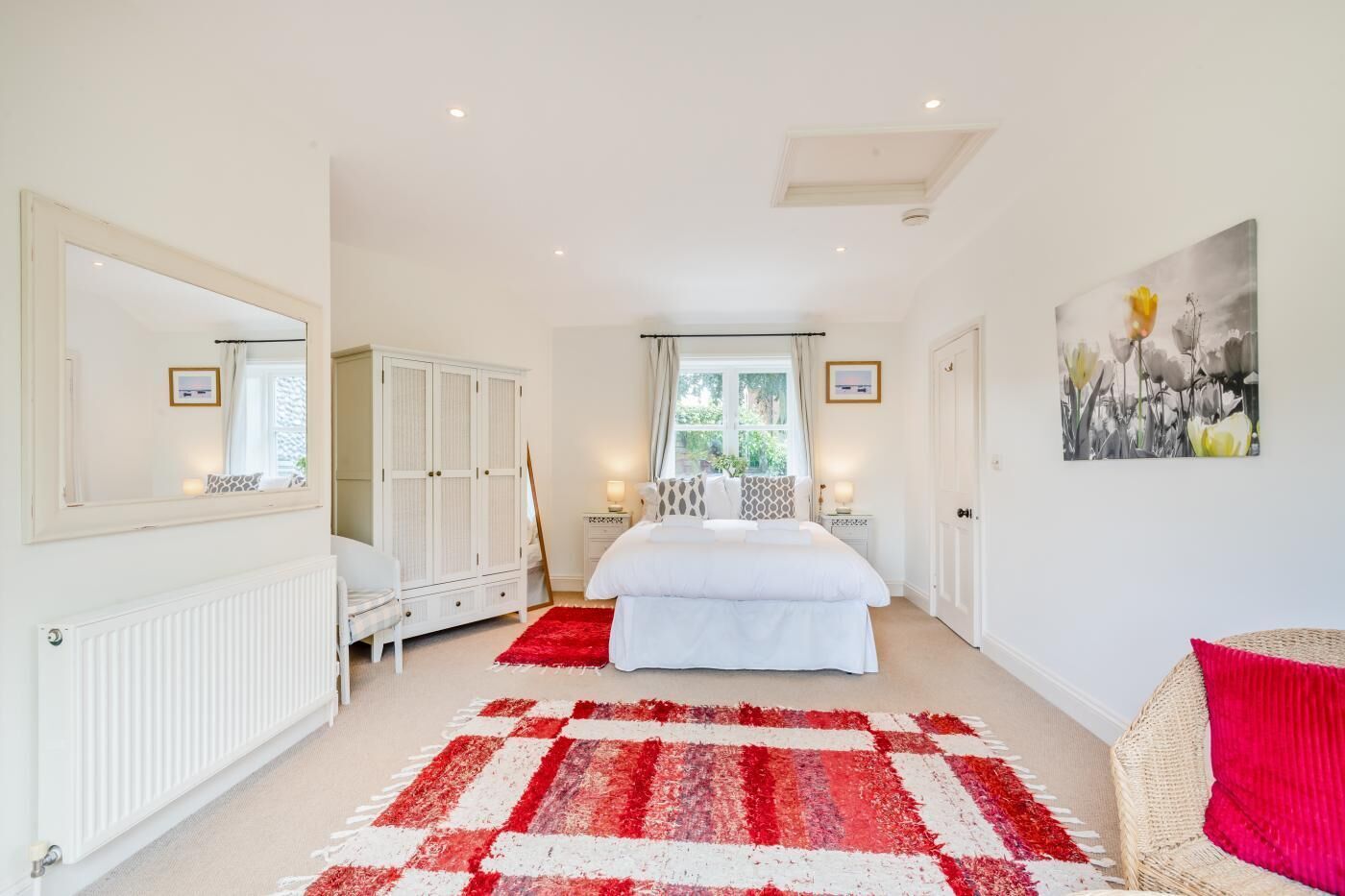 A bedroom with a large bed, a wardrobe, a radiator, and a red and white checkered rug.
