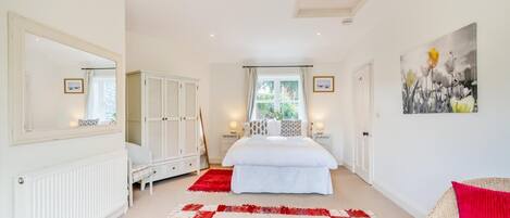 A bedroom with a large bed, a wardrobe, a radiator, and a red and white checkered rug.