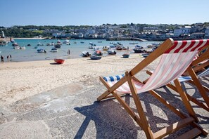 Une plage avec des bateaux, une chaise et une ville en arrière-plan.