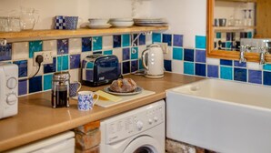 Een praktische keuken met een wasmachine, een broodrooster, een waterkoker en een koffiezetapparaat op het aanrecht.