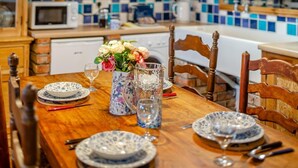 Een houten eettafel gedekt met blauwe en witte borden, een karaf en een vaas met bloemen.