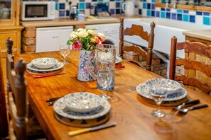 Ein Holztisch ist gedeckt mit blauen und weißen Tellern, einer Kanne und einer Vase mit Blumen.