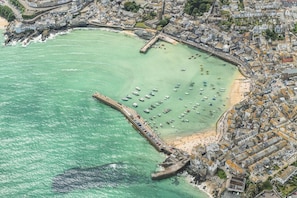 An aerial view of a coastal town with a marina, buildings, and a pier.