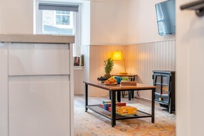 Une pièce chaleureuse avec une table mise pour le petit-déjeuner, une lampe, une bibliothèque et une cheminée.
