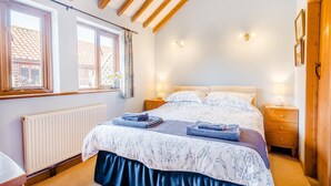 Een slaapkamer met een bed, twee nachtkastjes, een raam en een radiator.