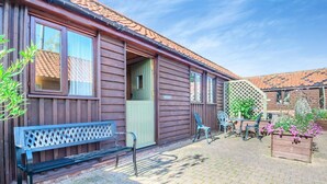 Una casa in legno con un patio, inclusi una panca, sedie e un tavolo.