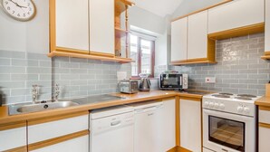 Una cucina moderna con mobili bianchi, una lavastoviglie Bosch, un forno Bosch, un microonde e un tostapane.