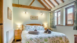 A bedroom with a wooden bed, two bedside lamps, a radiator, and a window with curtains. - 2 Bed in Wissett (oc-hfleet) (Wissett)
