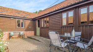 A wooden house with a tiled roof, a patio with a table and chairs, and a bench. - 2 Bed in Wissett (oc-hfleet) (Wissett)