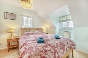 A bedroom with a bed, two bedside tables, a window, and a radiator. - 3 Bed in Broad Haven (oc-c27945) (Broad Haven)