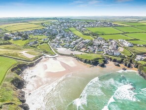 Ein Luftbild einer Küstenstadt mit Strand, Wohngebieten und grünen Feldern.