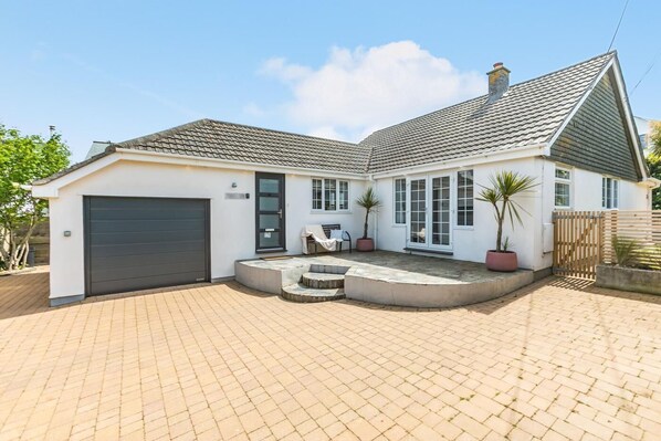 Ein zweistöckiges Haus mit Garage, einer Veranda und Topfpflanzen.