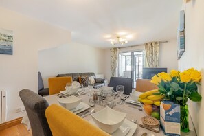 A dining area with a table set for four, a sofa, and a view of the outdoors. - 3 Bed in Marazion (oc-s27976) (Marazion)